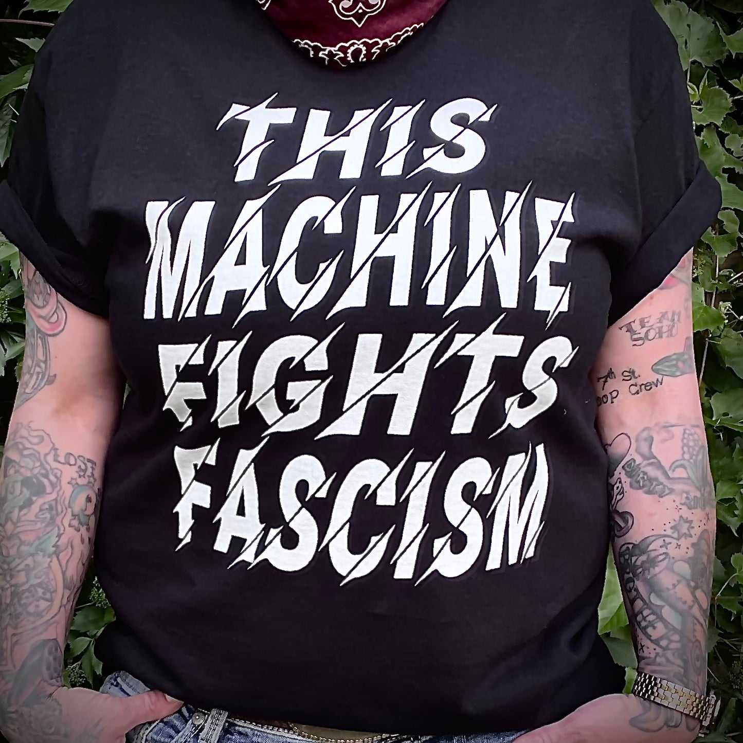 Model wearing t-shirt that reads This Machine Fights Facism in bold white lettering